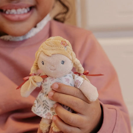 Child holding a small doll with blonde hair and a pink floral outfit.
