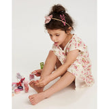 Young girl in a floral dress playing with nail polish on a white background