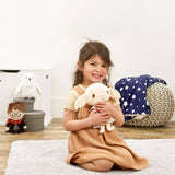 Young girl holding a plush soft toy Dobby character from Harry Potter. Big ears and a smiling face wearing his pillowcase a room with toys and a blanket on the floor.