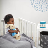 Child in a crib holding Peter Rabbit soft toy with a musical night light 