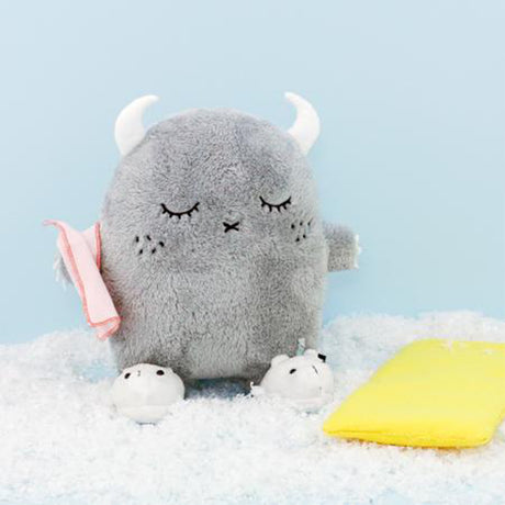Gray soft toy with horns and a towel and slippers on a light blue background