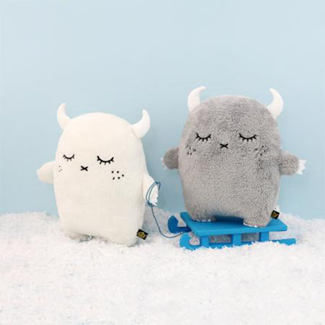 Two plush soft toys, one white and one grey, on a blue sled against a light blue background.