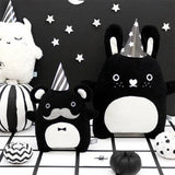 Black and white bunny soft toy with heart shaped nose standing next to other soft toys