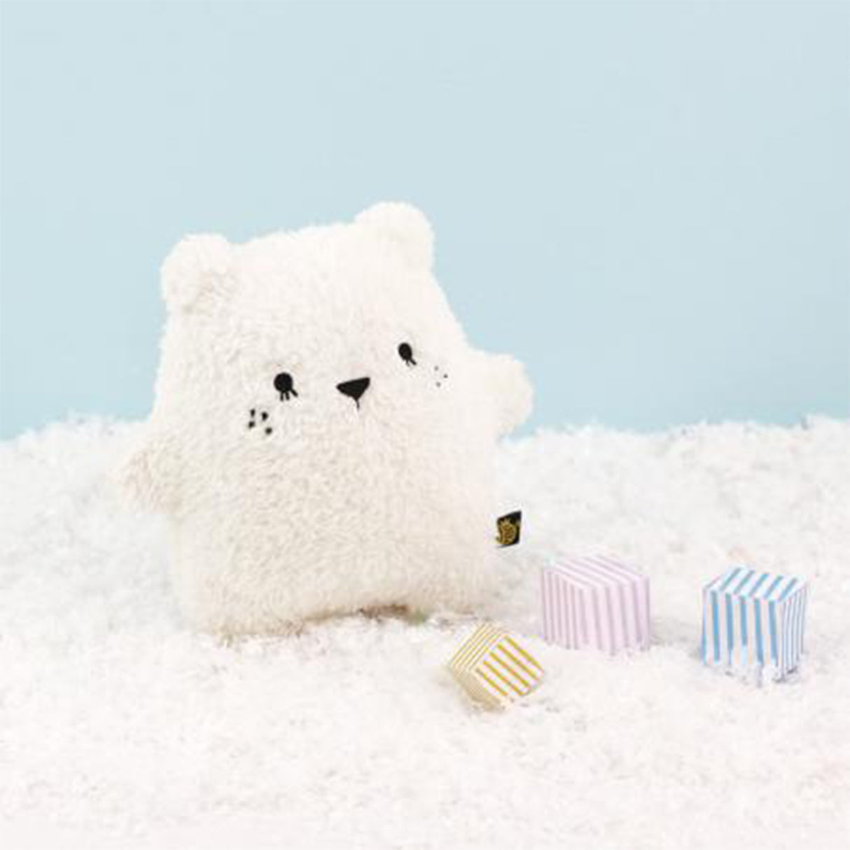 Polar bear soft toy on a fluffy snowy surface with blue background