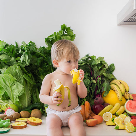 Child surrounded by fruits and vegetables in a kitchen setting