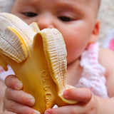 Baby holding a banana-shaped toy with 'Ol & Co' branding