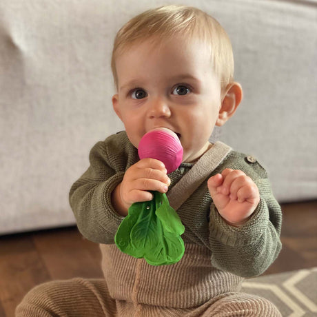 Baby chewing on a rubber teether rattle in the shape of a raddish