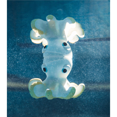 Octopus-shaped bath pool toy with black and blue eyes on a blue water background