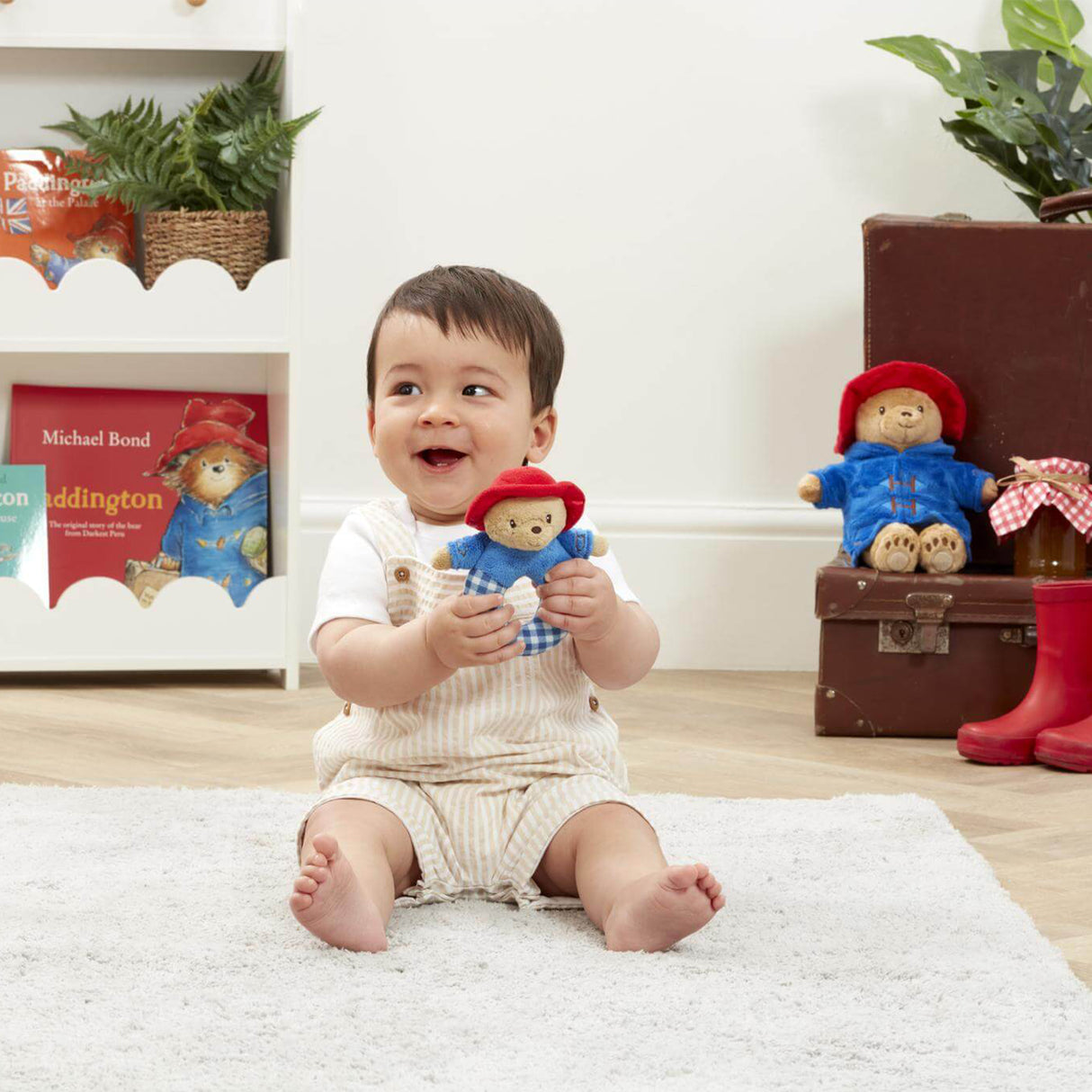 Baby holding a Paddington Ring rattle toy in a room with Paddington Bear-themed decor