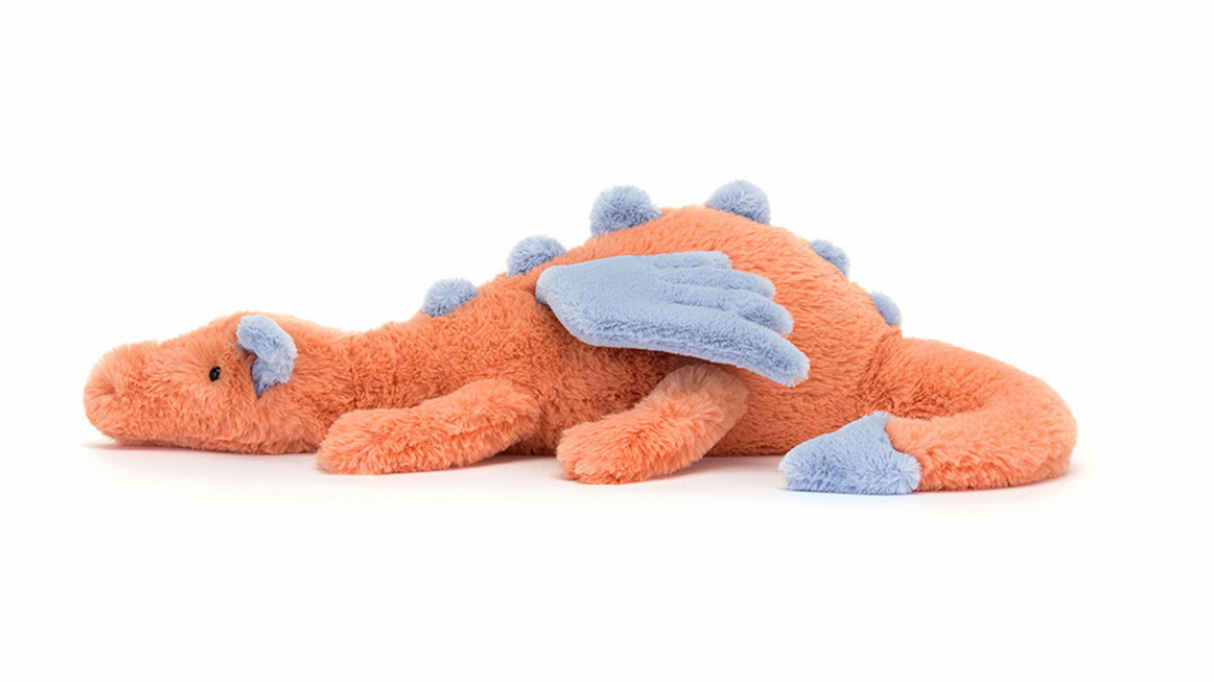 A plush toy representing a dragon with coral and blue colors, lying down with a content expression.