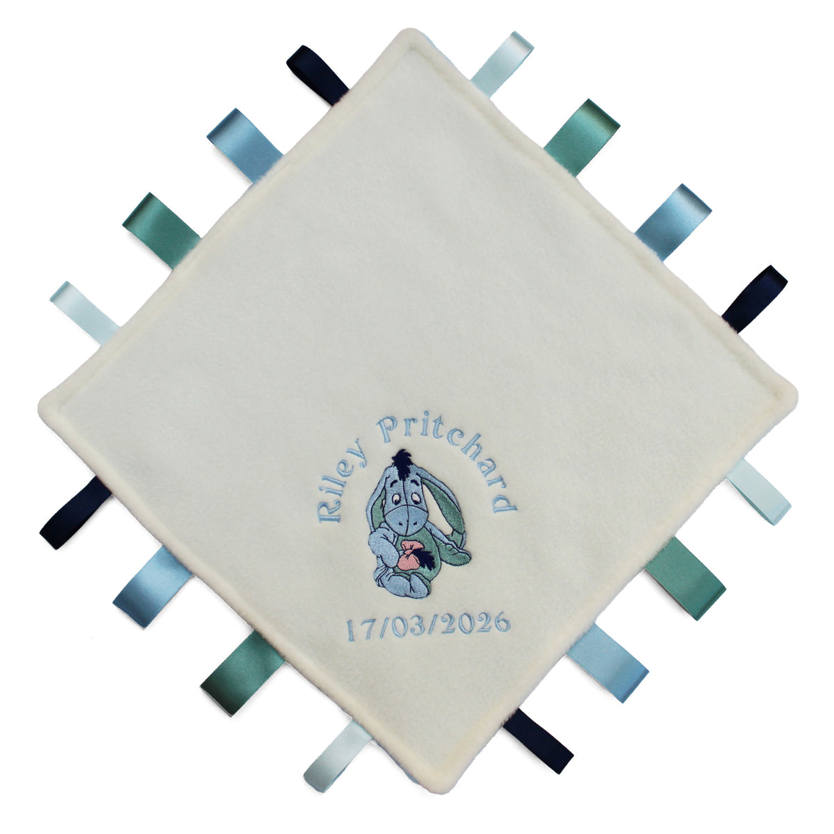 A personalised cream-coloured baby sensory lovey blanket with embroidered text and a cartoon eeyore character, surrounded by colourful ribbons on the edges.