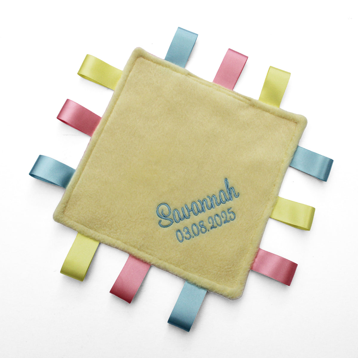A personalised baby taggy comforter with soft yellow fleece front, embroidered with the name and date of birth