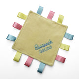 A personalised baby taggy comforter with soft yellow fleece front, embroidered with the name and date of birth