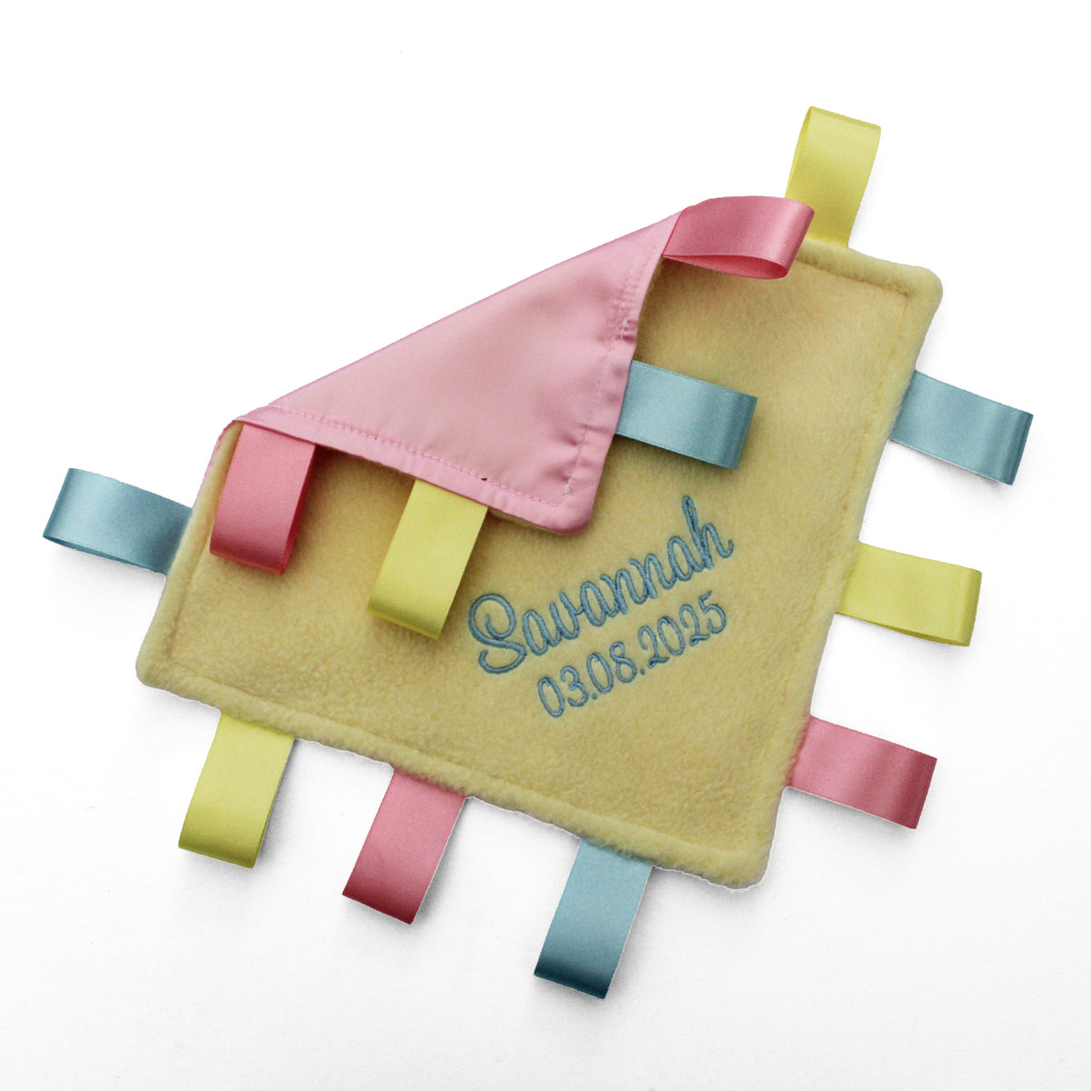 A personalised baby taggy comforter featuring a soft yellow fleece front, a pink satin backing, and colourful satin ribbons in pink, yellow, and blue.
