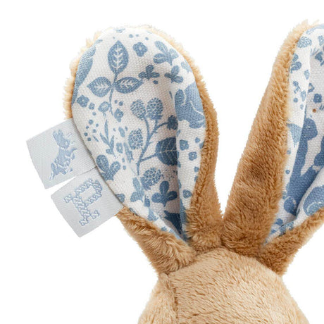 Close-up of a plush bunny toy with floral ears and tags on a white background
