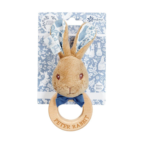Plush Peter Rabbit toy with wooden ring and bow tie on a floral-patterned card.