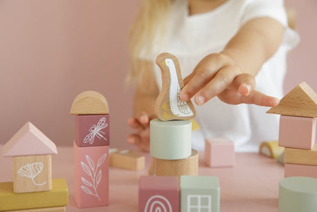 Pink and green wooden building blocks with various shapes and sizes, decorated with pictures such as goose and dragonfly, stacked together