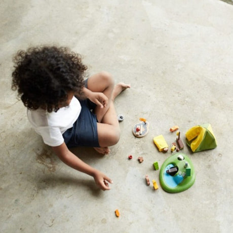 Child playing with camping set toys on a light-colored floor