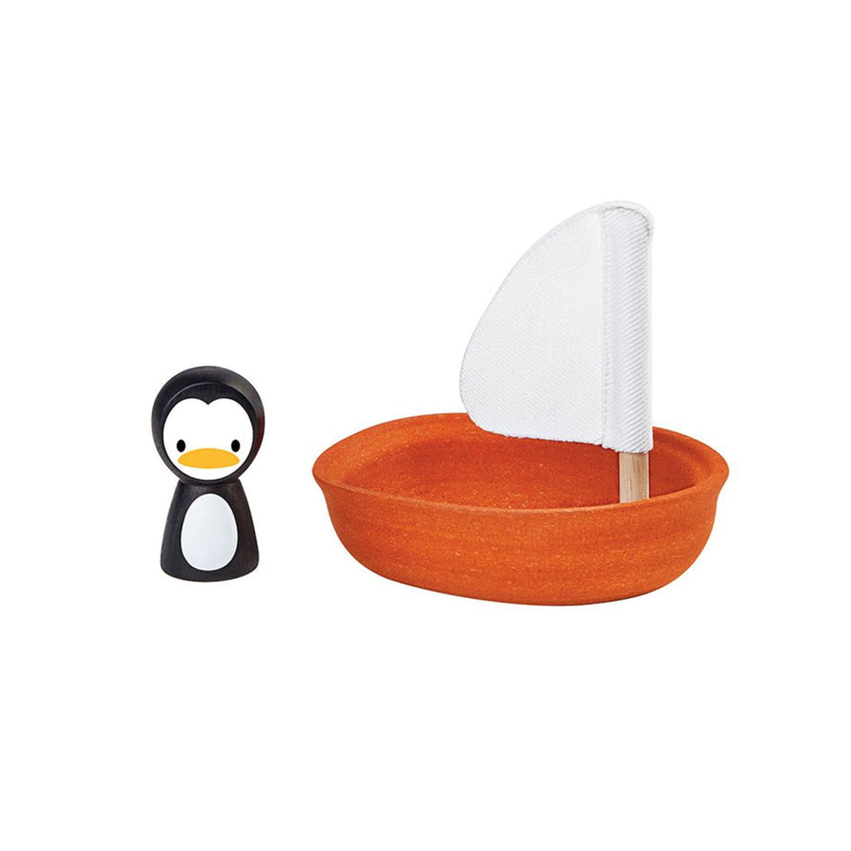 Small orange toy boat with a white sail and a penguin figurine on a white background