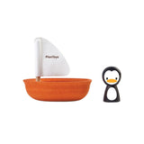 Toy sailboat with white sail and penguin figure on a white background, featuring PlanToys branding.