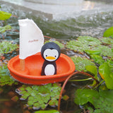 Penguin toy with a sailboat on a pond