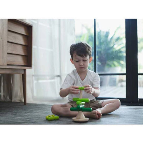 Child playing with a green tree toy in a bright room