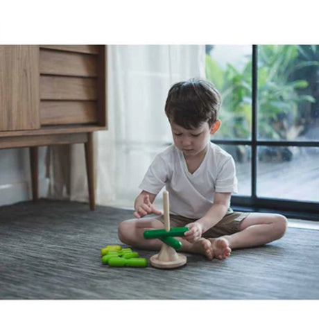 Child playing with Green wooden Stacking tree toy with a natural wood base on a white background