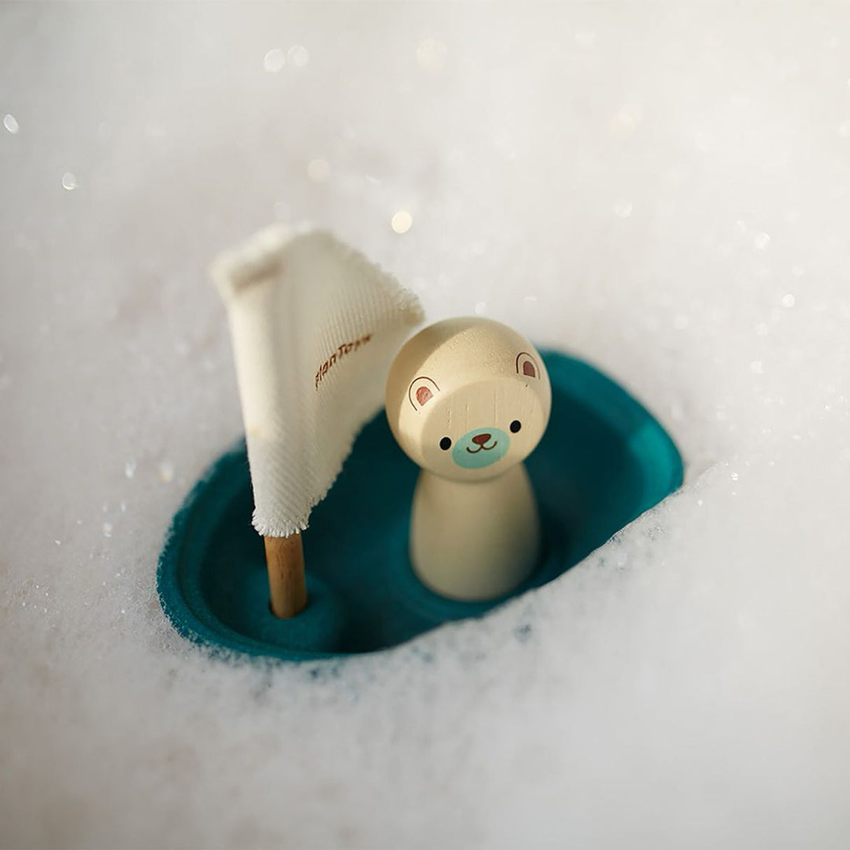 Toy polar bear with a small boat on a bubble bath background