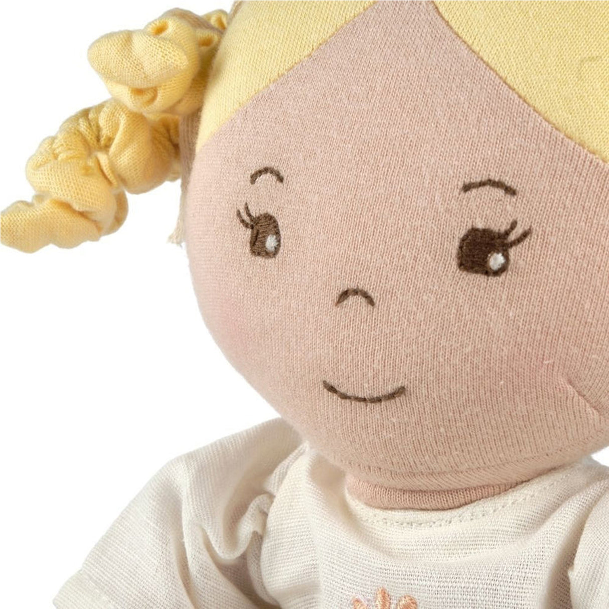 Close-up of a soft toy with a face, hair, and outfit on a white background
