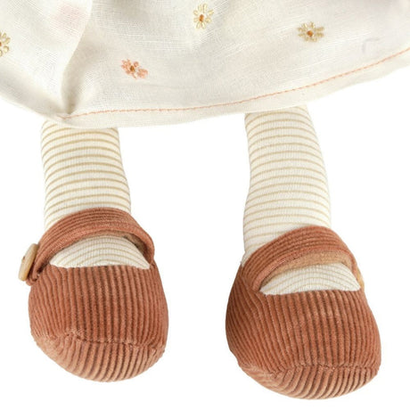 Close-up of a doll's legs wearing striped socks and brown shoes on a white background