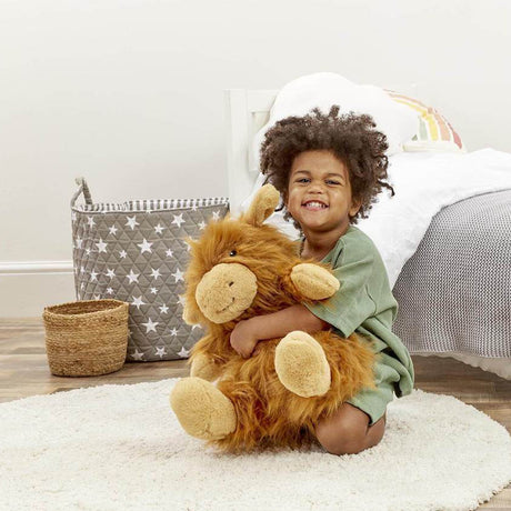 Child holding a highland cow toy in a room with a basket and star-patterned bag.