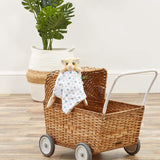 Wicker toy prram with a plush lion king baby soother on a wooden floor.