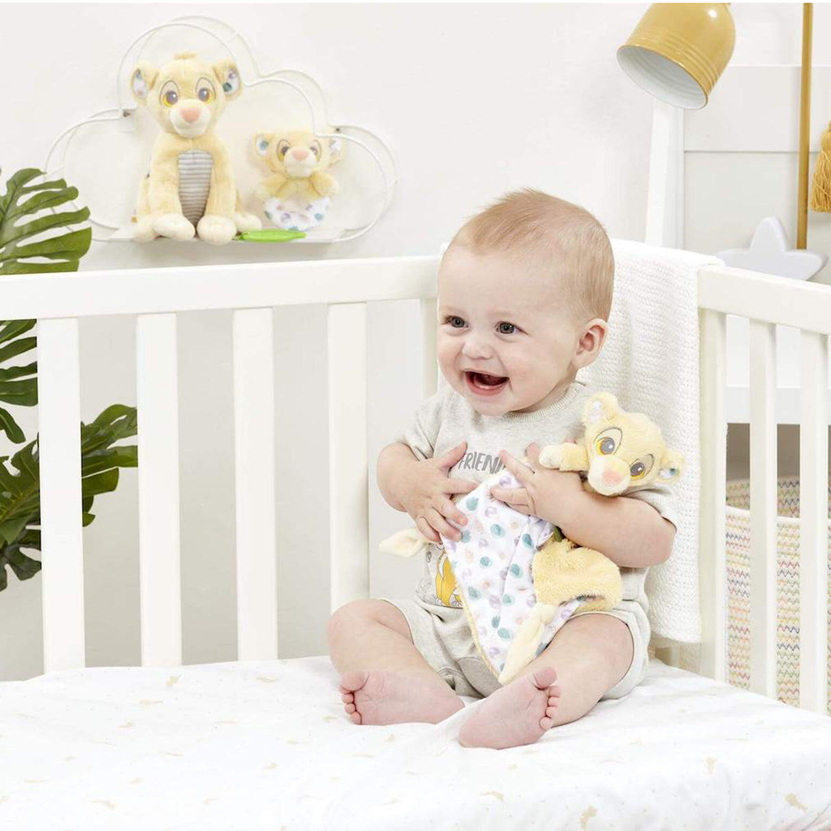 Baby sitting in a crib with lion king soother  in a nursery setting
