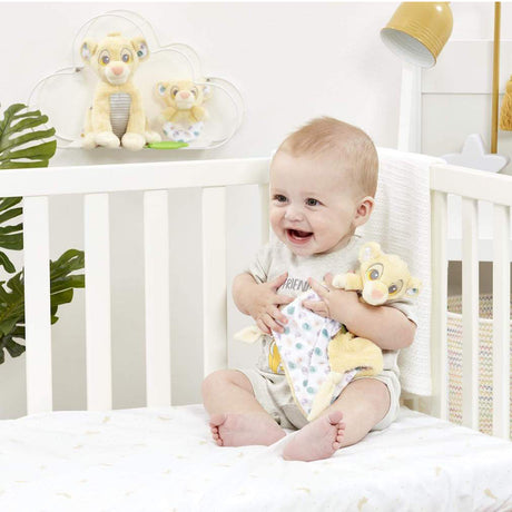 Baby sitting in a crib with lion king soother  in a nursery setting