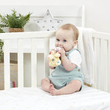 Baby sitting in a crib holding a Disney Lion King ring rattle with a white crib and decorative elements in the background.