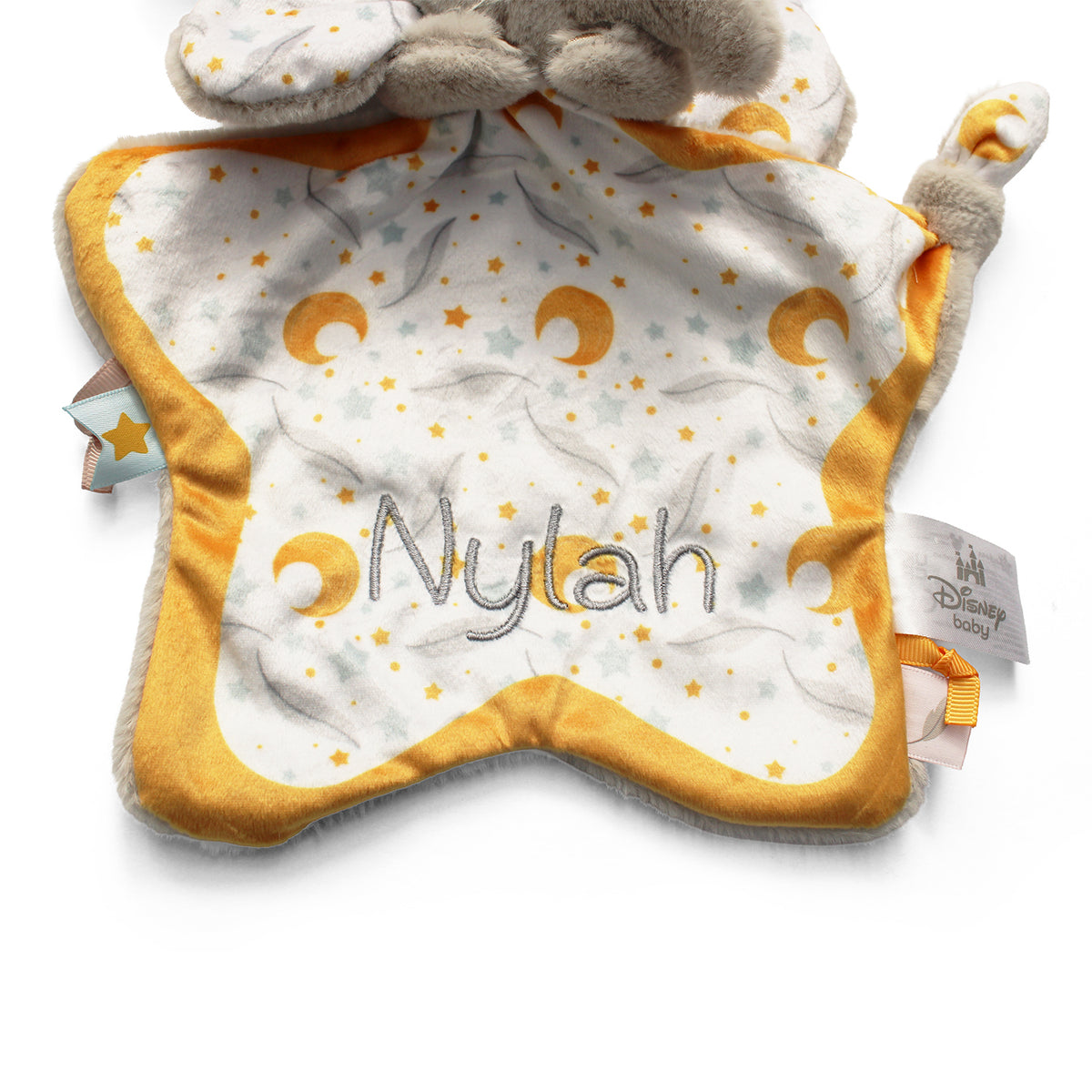 A star-shaped Disney Baby comforter toy with a plush printed with yellow crescent moons and stars, a mustard yellow border, and the name embroidered in grey.