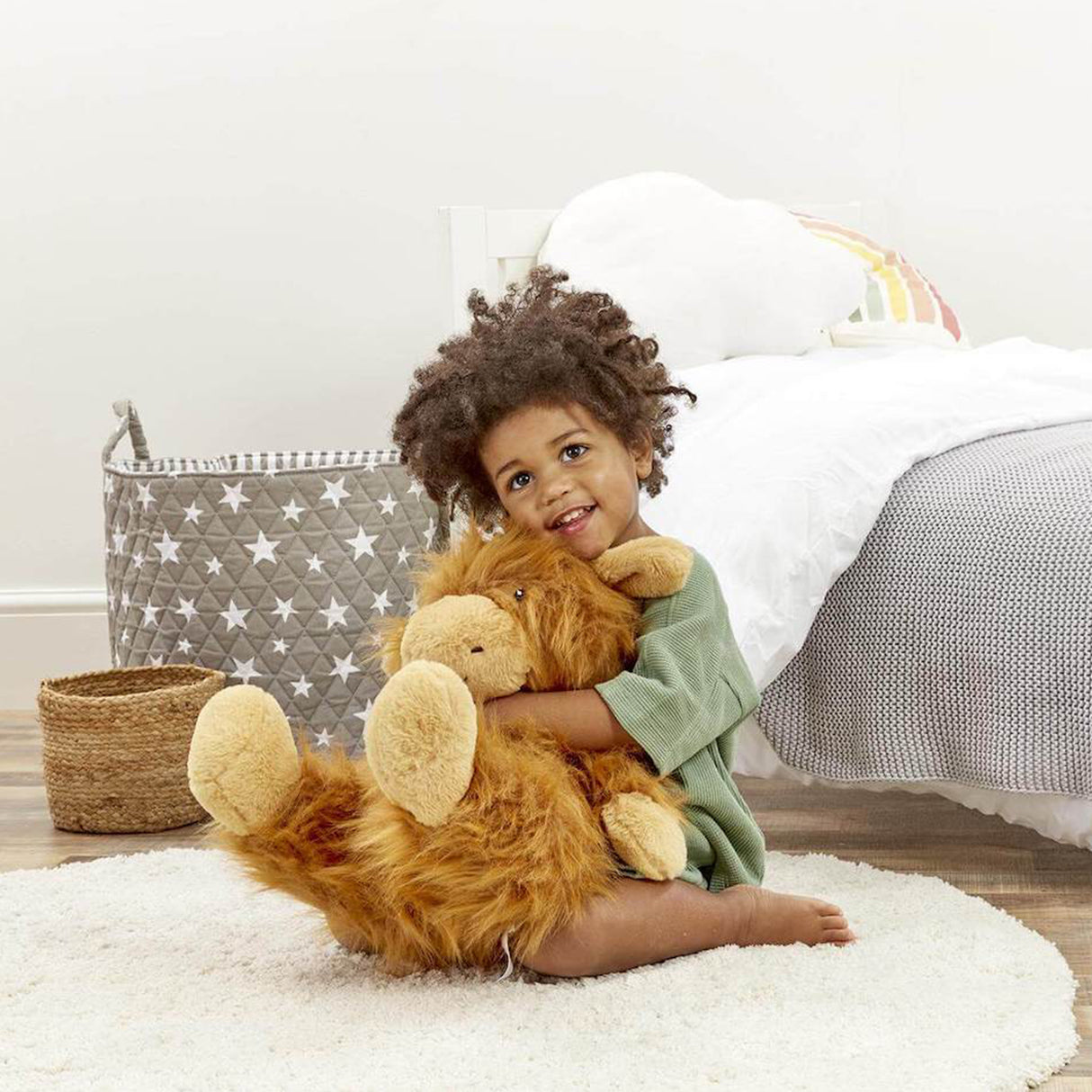 Child holding a large soft highland cow toy in a bedroom setting