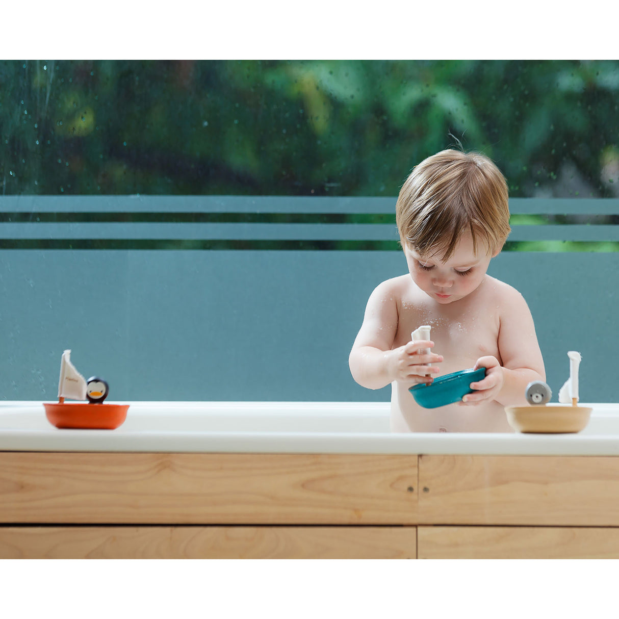 Child playing with boat toys in a bathtub outdoors