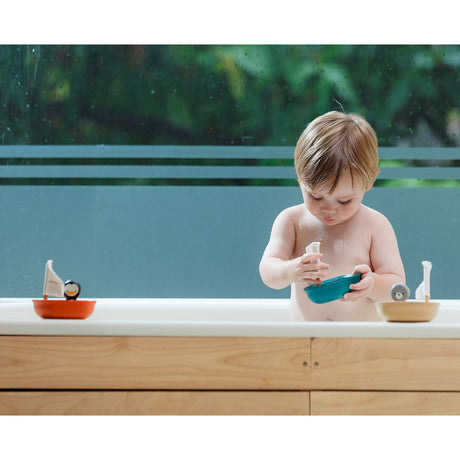 Child playing with boat toys in a bathtub outdoors