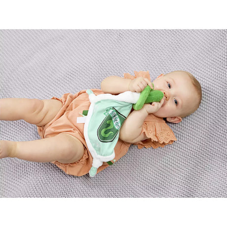 Baby lying on a textured surface with a plush Slytherin comfort blanket with a green and white color scheme, featuring a snake design, Slytherin crest, and embroidered stars.