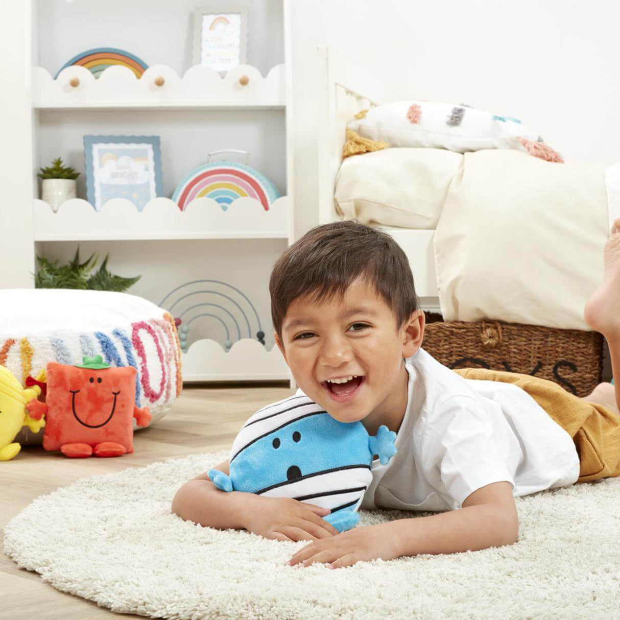 Child lying on rug in bedroom hugging Mr Bump soft toy with Mr square in the background