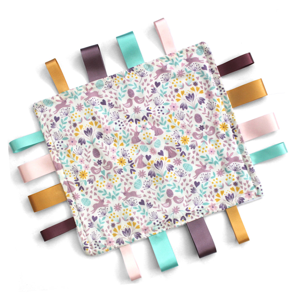 Fabric Baby taggy blanket with colourful ribbons on a white background