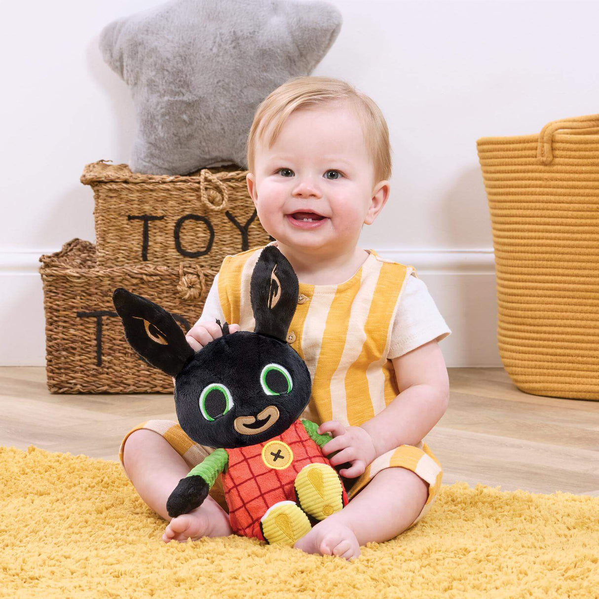 Child holding a Bing rabbit soft talking toy on a yellow rug