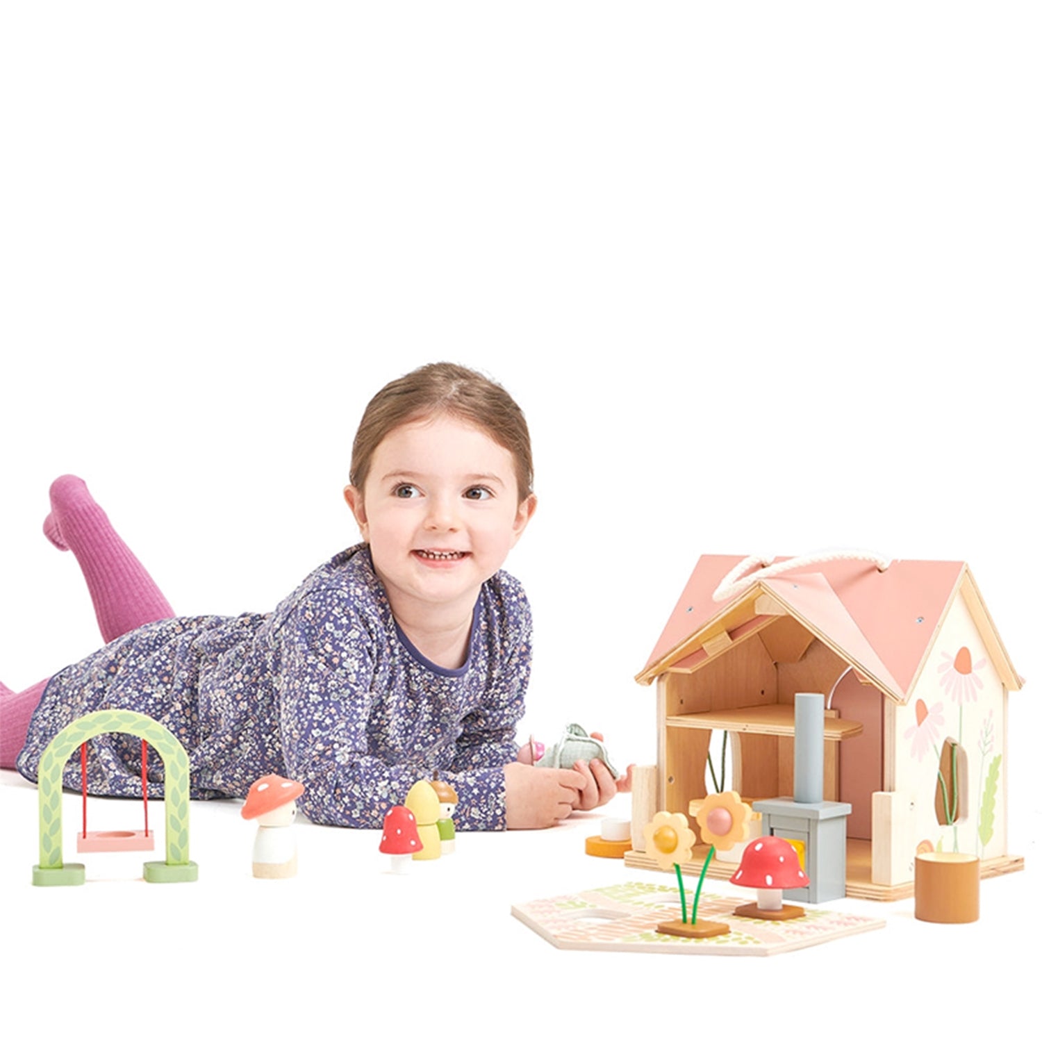Little girl playing with wooden toy house with colorful characters on a light surface