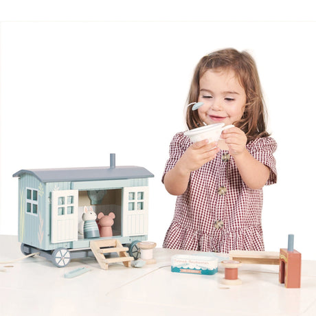 Child playing with a toy Shepherd Hut and accessories on a white background