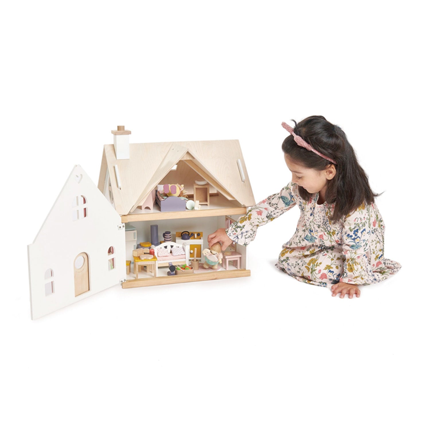 Child playing with a wooden dollhouse on a white background