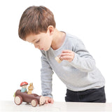 Child playing with a wooden toy car on a white background