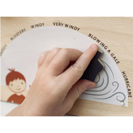 Hand using a tool to interact with a wind gauge on a wooden board