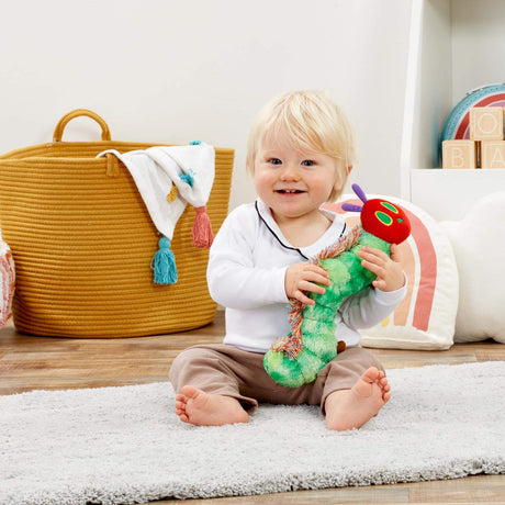 Child playing with a very hungry caterpillar toy in a room with a yellow basket and colourful decorations.