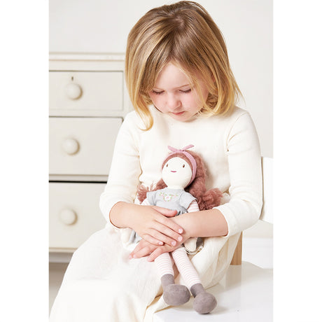 Young girl holding a rag doll in a softly lit room.